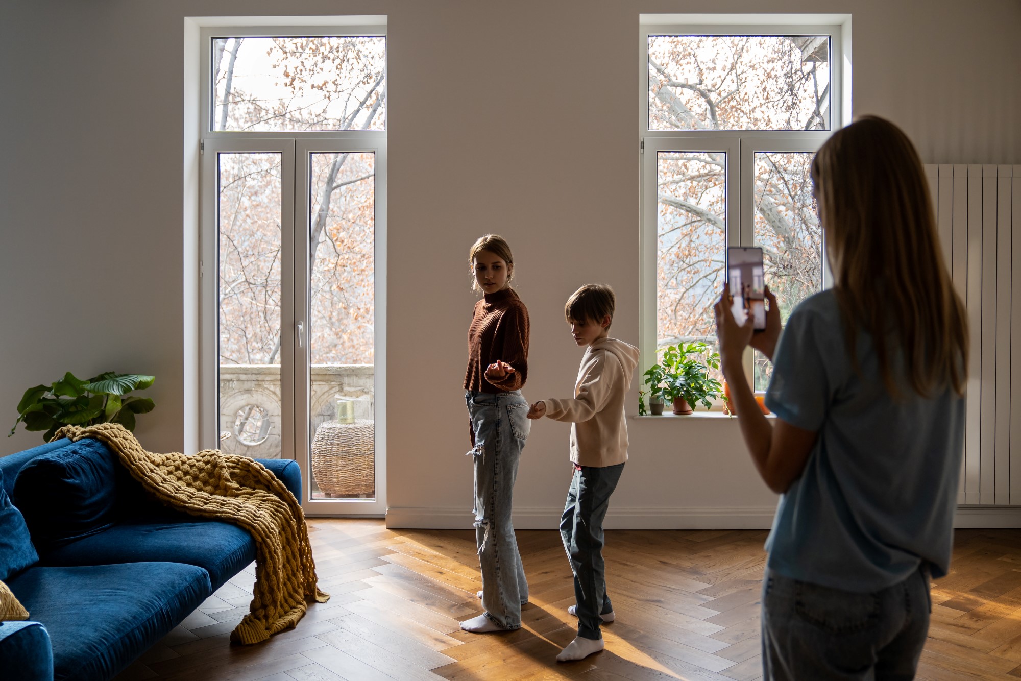 Family of three mother and two kids making social media content video on smartphone